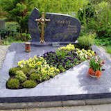 Doppelgrab mit Grabstein, Bronzekreuz und Grabbepflanzung